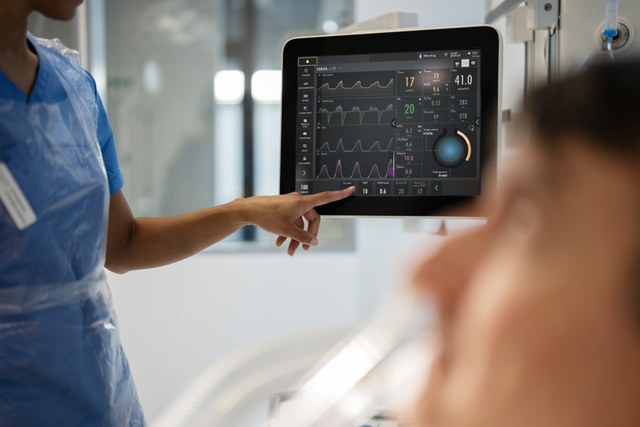 Servo-u product in clinical environment. Nurse pointing at a screen with nava edi signals showing a patients face in foreground