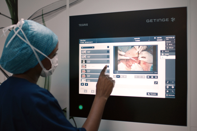 A medical professional uses a touchscreen displaying surgical images in an operating room.