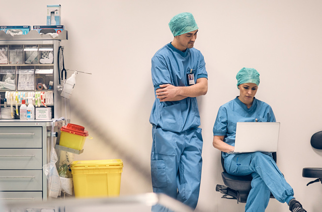 Hospital staff in storage area looking at laptop screen