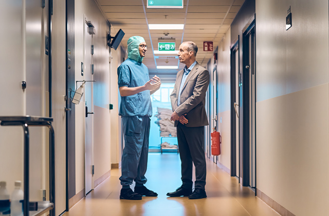 Doctor and businessman talking in a hospital corridor